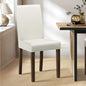 White chair with wooden legs in a room with a table and decorative items.